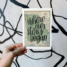 Load image into Gallery viewer, A vintage style map design of the state of Georgia with black lettered text "where our story began" over the print. The map is held in front of a white backdrop with spiraling black lines by a white woman.