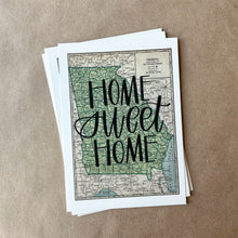 Load image into Gallery viewer, Stack of horizontal sheets of paper; the top sheet is a vintage style map design of the state of Georgia with black lettered text "Home Sweet Home" over the print. The paper is lying on a large piece of brown paper.