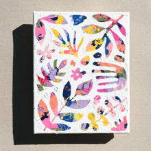 Load image into Gallery viewer, A colorful abstract painting painted over with white to show designs of plants and nature in the negative space. The painting is laying on a tan canvas.