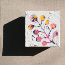 Load image into Gallery viewer, A colorful abstract painting with colors pink, purple, yellow, orange, blue, and black painted over with white to show a plant in the negative colored space. The painting is laying on a tan canvas.
