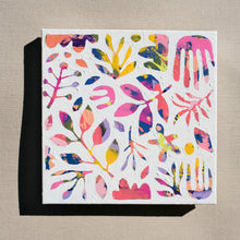 Load image into Gallery viewer, A colorful abstract painting painted over with white to show designs of plants and nature in the negative space. The painting is laying on a tan canvas.