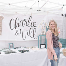 Load image into Gallery viewer, Owner, Kirsten McClendon, standing in front of her Charlie & Will booth were she is selling her handmade goods for littles. Behind Kirsten is a large white banner with the handlettered logo in black.