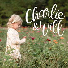 Load image into Gallery viewer, Handlettered white Charlie & Will logo on a photo of a young girl standing in a zinna field of flowers wearing a Charlie and Will dress.