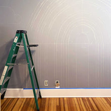 Load image into Gallery viewer, Beginning sketches of A's rainbow. Chalked out lines of the rainbow are on the dark grey wall.