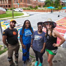 Load image into Gallery viewer, One man and three woman smile for a picture in front of the completed crosswalk with view of horizontal and vertical crosswalk designs