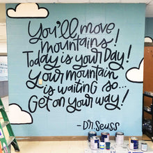 Load image into Gallery viewer, Blue painted mural with text "you'll move mountains! today is your day! your mountain is waiting so... get on your way! -dr. seuss" with clouds and black lettering