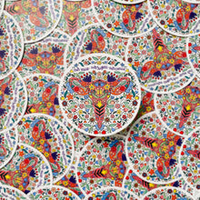Load image into Gallery viewer, A red uterus surrounded in colorful designs of flowers and leaves under purple text "our voice • our rights • our choice". The sticker is in front of a pile of the same sticker.