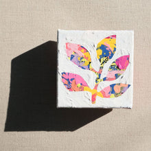 Load image into Gallery viewer, A colorful abstract painting with colors pink, purple, yellow, orange, blue, and black painted over with white to show a stem with leaves in the negative colored space. The painting is laying on a tan canvas.
