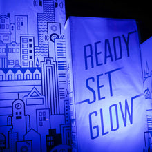 Load image into Gallery viewer, Photo of fabric banners, left has a graphic design of a cityscape and the right says &quot;ready set glow&quot; with a blue light tint

