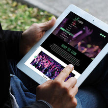 Load image into Gallery viewer, Photo of a man&#39;s hands holding an ipad on &quot;5k dance party&quot; website with blurred greenery and sidewalk in the background
