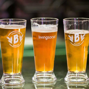 Three beer glasses resting on a glass table. The two outside glasses have the Beer Fest "B" logo and the middle glass says "living social"