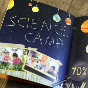 Designed page of a book with blue map style background with planets at the top and words "science camp" in the middle. 