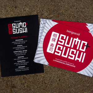Two living social prints stacked next to eachother on granite background. The left is a menu for "sumo sushi" and the right is an advertisement for "sumo sushi" with a red circle and lines in the background.