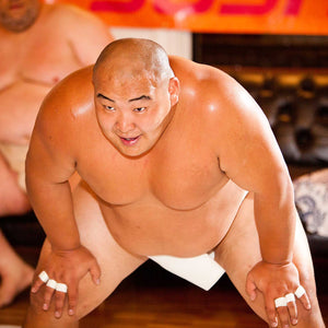 Photo of a male sumo wrestler resting his hands on his knees