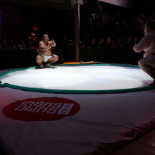 Load image into Gallery viewer, Photo of a sumo wrestling ring with two sumo wrestlers assuming form for their match in dim lighting
