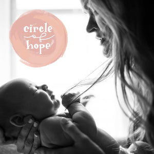 A black and white picture of mother holding her child and in the top left corner there's the Circle of Hope logo. A logo consists of a circle of shades of pink with white lettering inside. The lettering says "circle of hope" where "circle" and "hope" are a hand drawn serif typography and "of" is a cursive monoline typography.