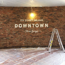 Load image into Gallery viewer, In the middle of installing the 7th Street Salvage Downtown mural. Only the white typography is installed, saying, &quot;7th Street Salvage Downtown Macon, Georgia&quot;
