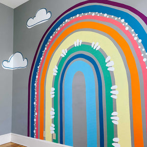 Final rainbow mural in A's bedroom. The rainbow is eggplant purple, navy blue salmon pink, orange, butter yellow, kelly green, navy, and cyan blue with white circle accents and flourishes. There are white clouds surrounding the rainbow with off centered navy outlines. 
