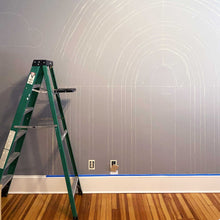 Load image into Gallery viewer, Beginning sketches of A&#39;s rainbow. Chalked out lines of the rainbow are on the dark grey wall. 
