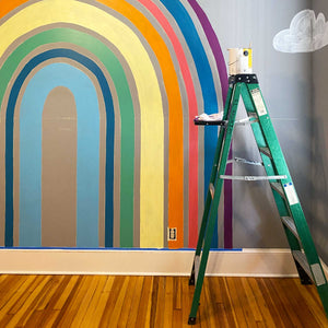 Mid process of installing A's rainbow. Each of the stripes has one coat of paint. The stripes are eggplant purple, navy blue salmon pink, orange, butter yellow, kelly green, navy, and cyan blue.