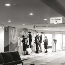 Load image into Gallery viewer, Black and white photo of seven people painting different parts of the macon airport mural
