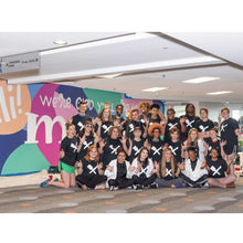 Load image into Gallery viewer, Twenty four painters for the mural smiling and posing with hands waving in front of the completed mural
