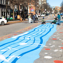 Load image into Gallery viewer, View of vertical road painted with blue and white paint with music notes and dots.
