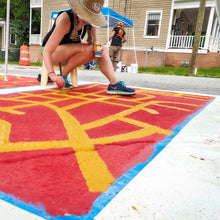 Load image into Gallery viewer, Mama Hawk painting crosswalk mural with orange and red paint
