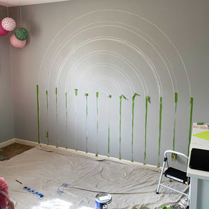The beginning of E's rainbow mural. A dark gray wall with the rainbow stripes chalked out and painter's tape in place to begin painting.
