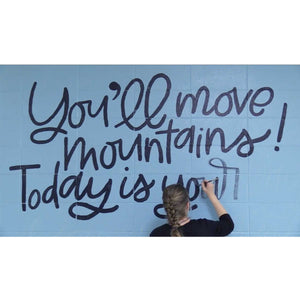 Mama Hawk Draws painting "you'll move mountains" black lettering on blue wall