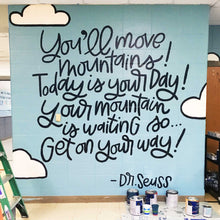 Load image into Gallery viewer, Blue painted mural with text &quot;you&#39;ll move mountains! today is your day! your mountain is waiting so... get on your way! -dr. seuss&quot; with clouds and black lettering
