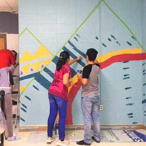 A boy and girl painting an abstract mountain on the adjacent wall of the mural 