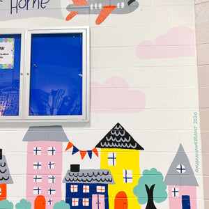 Close up of the right of the "habits at home" mural with buildings and trees and faint pink clouds