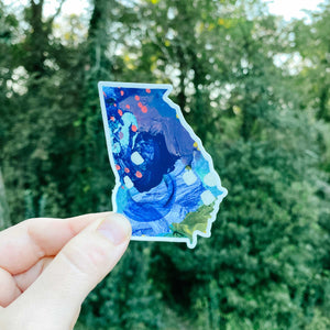 State of Georgia shaped sticker with abstract design and trees in the background
