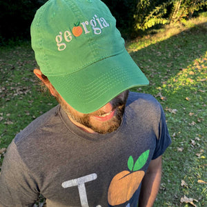 Close up of a man wearing a green hat with "georgia" text and greenery in the background