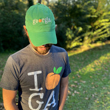 Load image into Gallery viewer, Man wearing a grey tee with &quot;I (orange peach) GA&quot; printed in the center, wearing green &quot;georgia&quot; hat.
