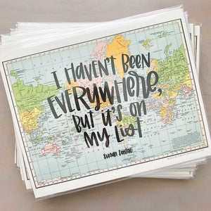 Stack of horizontal multicolored vintage style maps of the world with hand lettered text that says "I haven't been everywhere, but it's on my list" in black lettering