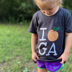 Young girl wearing the "i hear GA" tee with grass and trees in the background